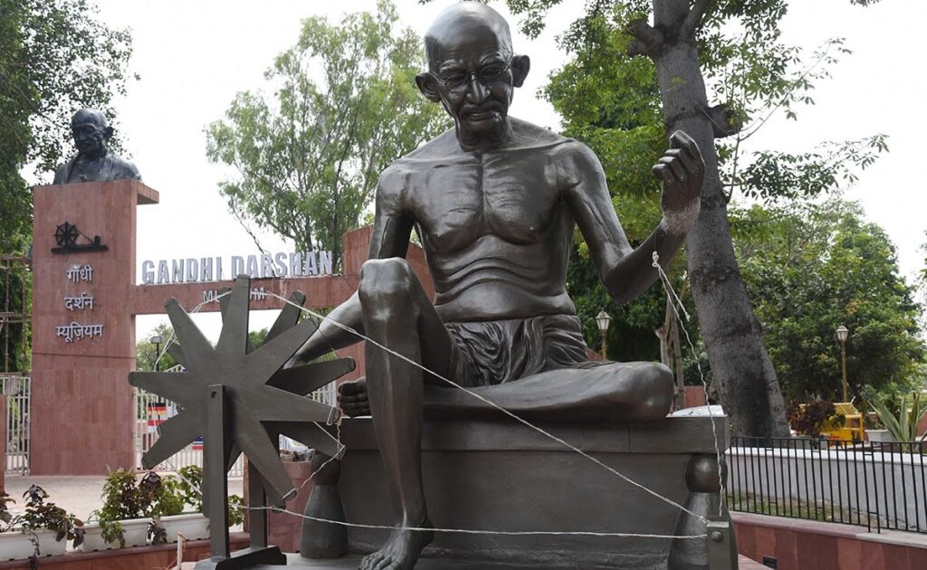 statue of Mahatma Gandhi spinning a charkha is installed at the entrance of Gandhi Vatika.